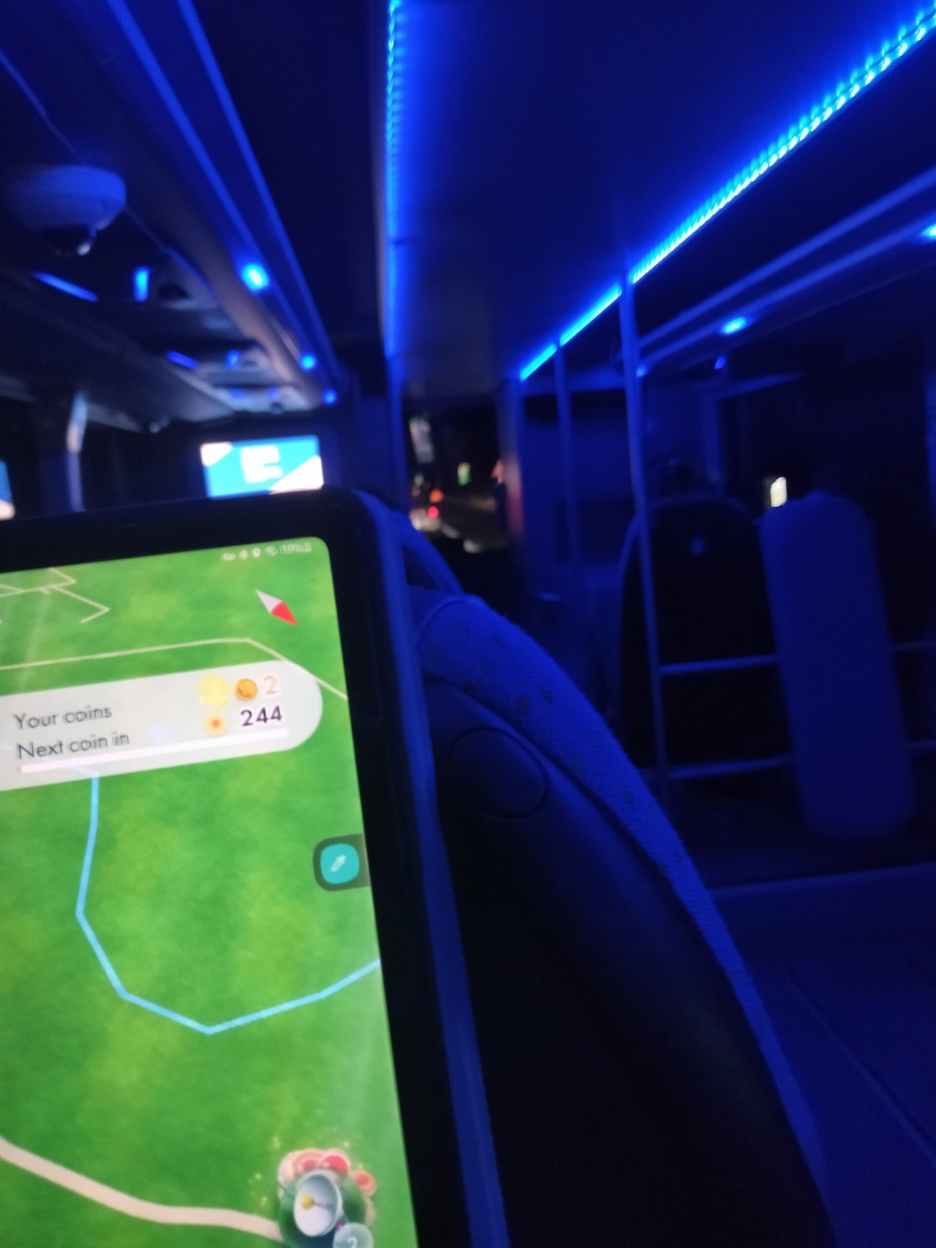 In bus con le luci blu, vista autostrada per uno spiraglio davanti, il tablet con Pikmin Bloom in mano